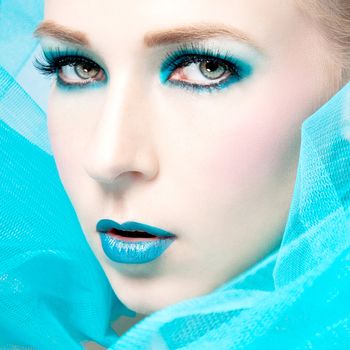 beautiful woman with extreme colorfull make up in turquoise portrait