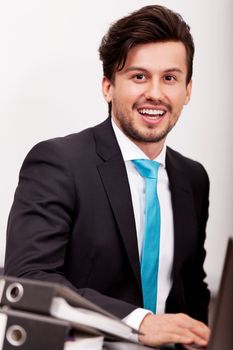 young businessman smiling at office with folders on desk