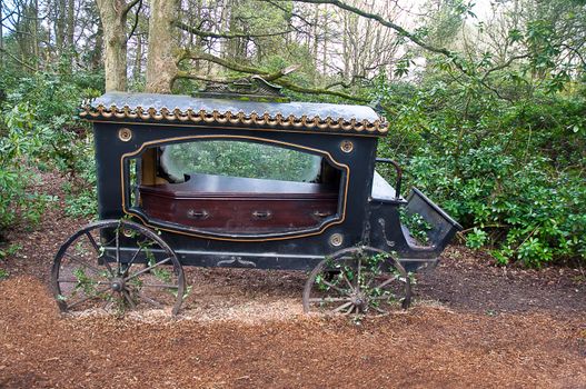 Broken-old coach hearse with the coffin being in the wood .