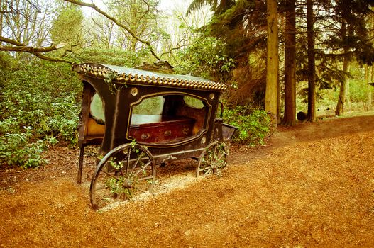 Broken-old coach hearse with the coffin being in the wood .