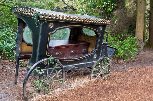 Broken-old coach hearse with the coffin being in the wood .