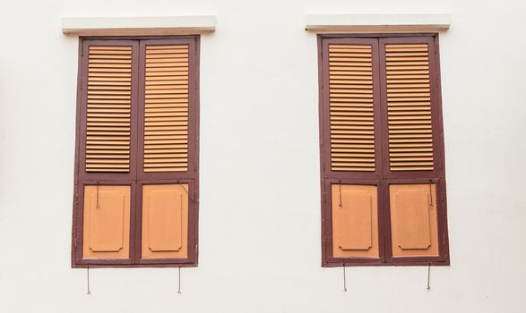 Two old wooden windows on plain wall