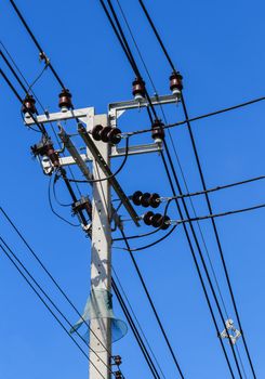 Electric pole with powerlines against bright blue sky with snake protector
