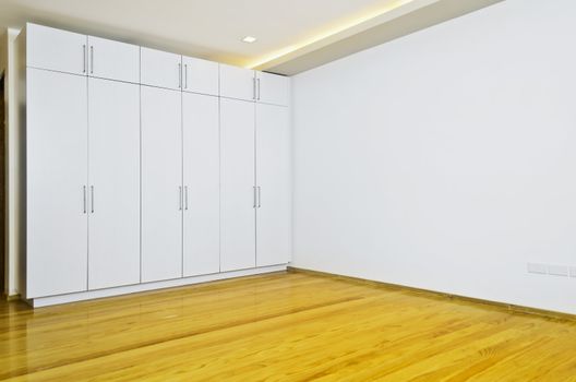 Newly built and painted room with wooden flooring and white cabinets