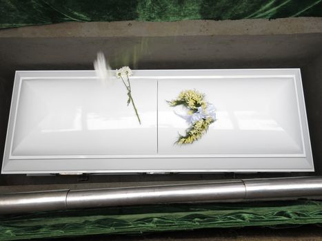 White coffin in grave during funeral