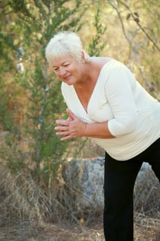 Smiling Senior woman exercising in leafy park .