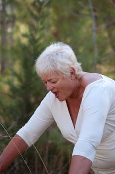 Smiling Senior woman exercising in leafy park .