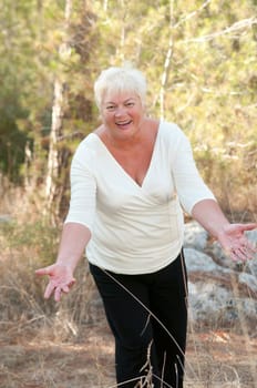 Smiling Senior woman exercising in leafy park .