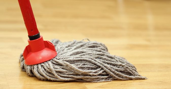 cleaning the wooden floor with an old red mop