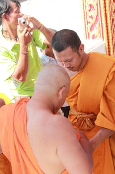 NAKON SI THAMMARAT, THAILAND - NOVEMBER 17 : The senior monk dress the new monk in the Newly Buddhist ordination ceremony on November 17, 2012 in Nakon Si Thammarat, Thailand.