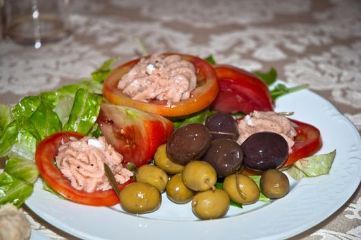 Salad of tomato with salmon oil, olives and salad .