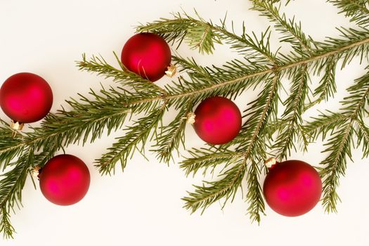 Border of red christmas garland with baubles and ribbons on white.