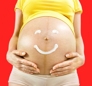 closeup body of pregnant woman on which smile is drawn