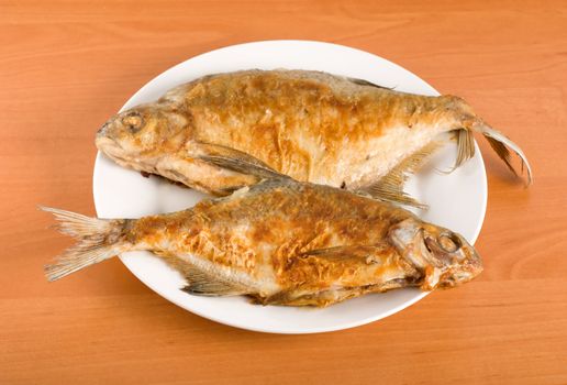 Roasted bream on the plate on a wooden table