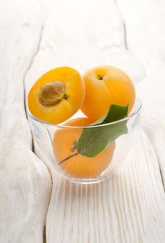 Apricots in a cup on a wooden background