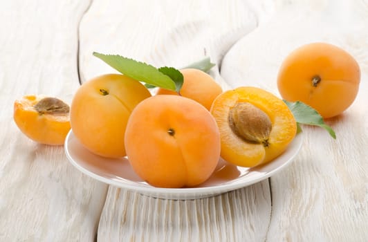 Apricots on the plate on a wooden background