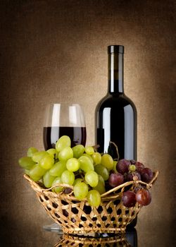 Bottle of red wine and grapes on a background canvas