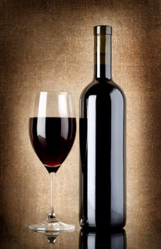 Wine bottle and wineglass on a background of old canvas