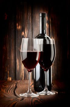 Two glasses of wine and wine bottle on a wooden background