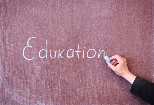 Word education written by man with chalk on blackboard.