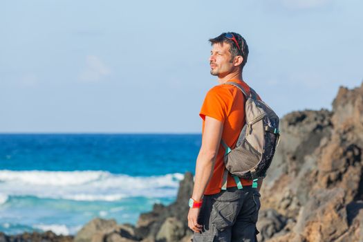 Sports young man with backpack. Background of the sea