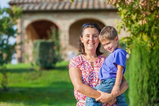 Portrait of a happy little boy with his mother in the garden