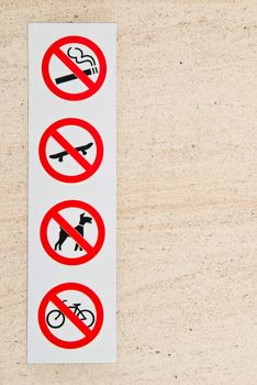 forbidden signs (smoking, skate, animal and bicycle) on a marble wall at the entrance of a shopping mall