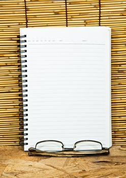 White notebook paper. The background is a wall of bamboo.