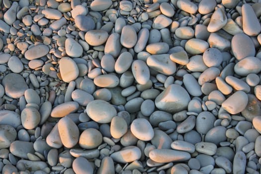 Pebbles on sea coast on sunset.