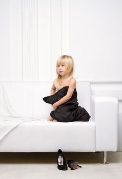 3 years old girl lying on a white sofa in my mother's dress, standing next high heels