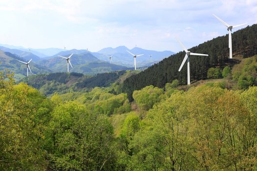 more wind turbines in the mountains on the horizon line on cloudy sky background