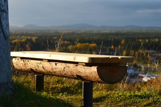 A bench of wood at a lookout with view of a woodland in northern Sweden