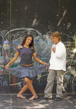 Portrait of of dancing boys and girls near a wall with graffiti.