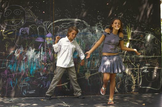 Portrait of  dancing boys and girls near a wall with graffiti.
