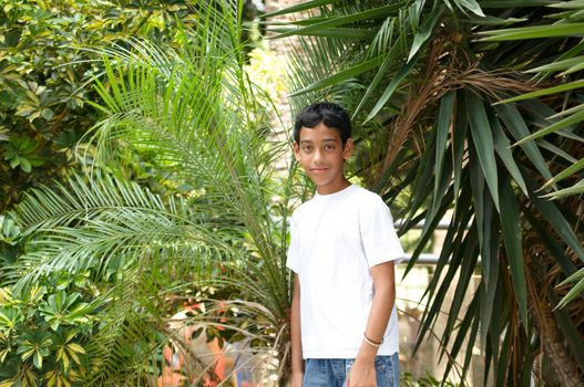 Portrait of a smiling boy in the background of tropical plants.
