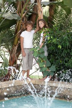 Children near the fountain surrounded by tropical plants.