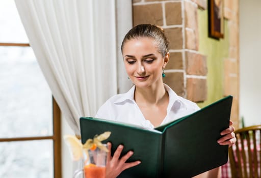 portrait of a nice lady at the restaurant, choosing dishes from the menu