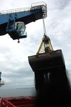coal is being loaded onto tankers with a blue crane