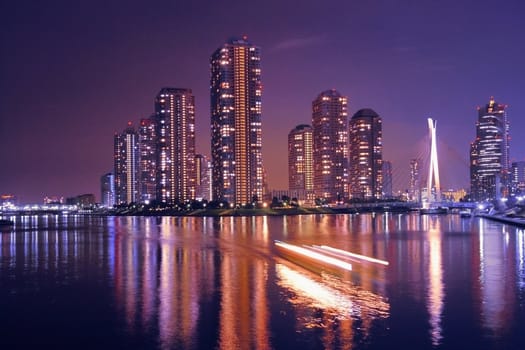  modern Tokyo buildings with night reflection in water and light traces of moving ship, Japan