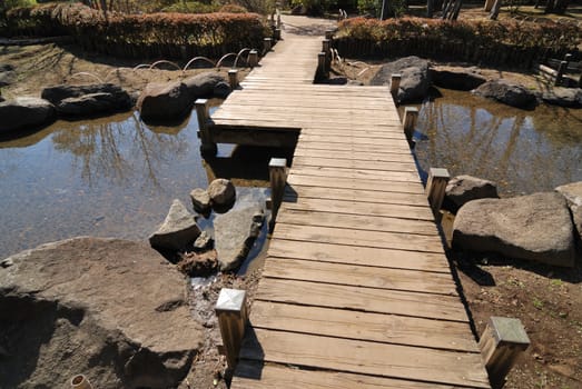 scenic wooden bridge in Japanese garden by bright sunny day