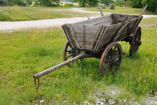 old style wooden wagon on the green meadow