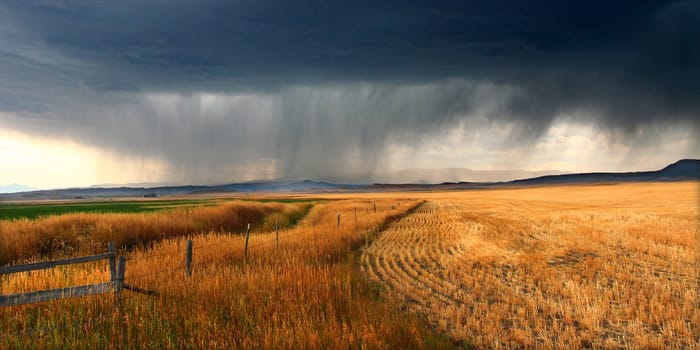 Dark storm clouds thunder across the plains of rural Montana on a fall day.