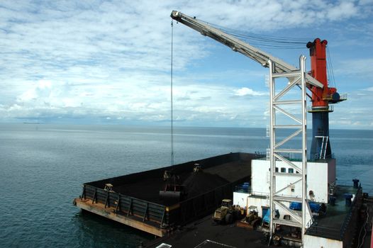 coal is being loaded onto tankers with a crane