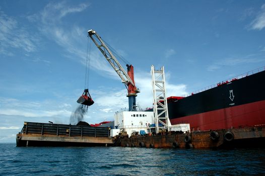 coal is being loaded onto tankers with a crane
