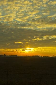 A beatiful sunset with cloudy sky over the fields