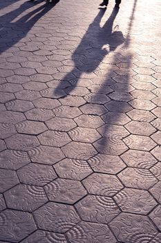 scenic tiled pavement of Barcelona streets with city lamp and woman shadows; focus on shadows