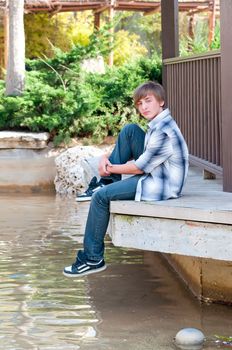 Portrait of a teenager on a background of water in the park.