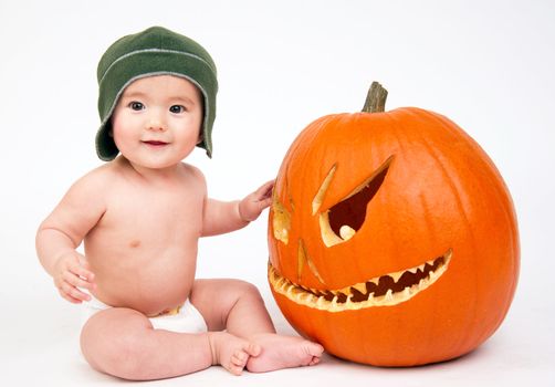 Young male sits next to a pumpkin on white