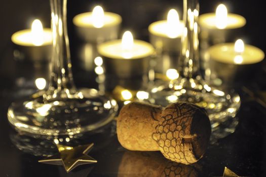 holiday still-life with Champagne cork , two glasses and many candles behind; focus on foreground cork