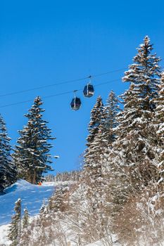 Alpine landscape. Ski lift chairs, pine tree, mountains. Tyrol, Austria